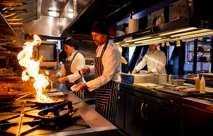 Chefs cooking beneath a commercial kitchen rangehood