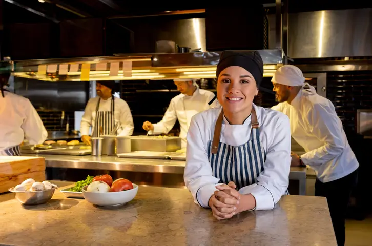 Chef working in a busy commercial kitchen beneath the exhaust canopy