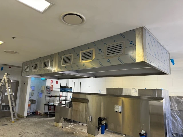 Stainless-steel commercial kitchen canopy installed above a cooking area
